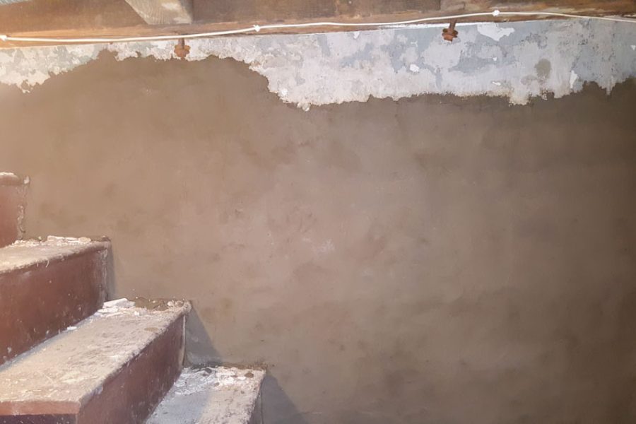 Parging basement wall beside a concrete stair for a stronger foundation