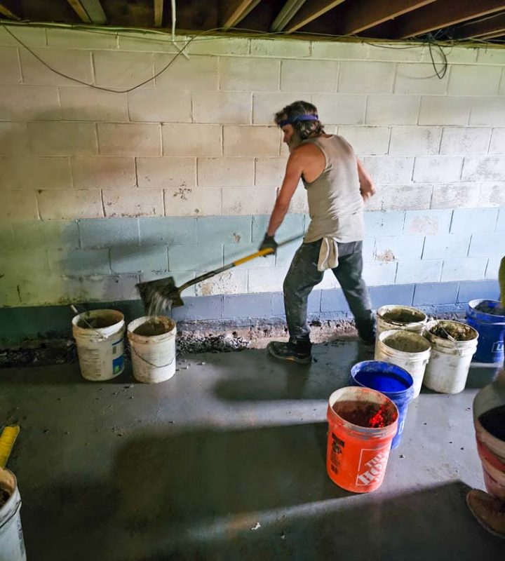 A skilled worker placing a cement or concrete over an area on the basement for waterproofing