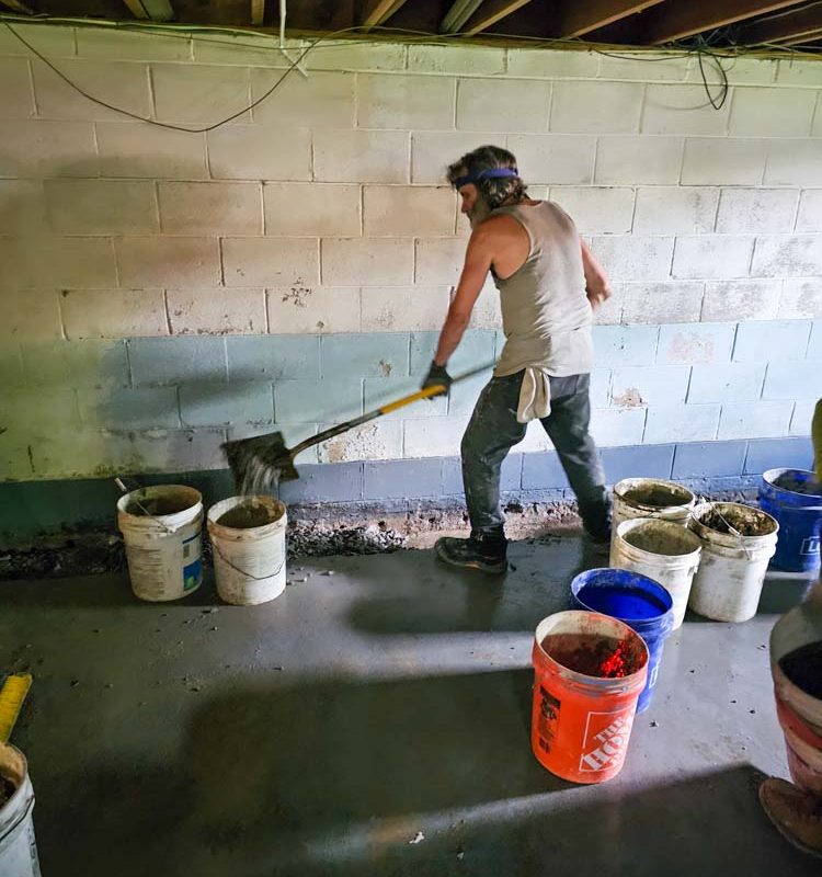 A skilled worker placing a cement or concrete over an area on the basement for waterproofing